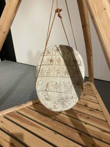 an oval drum hanging from a tripod, with figures across the drum face