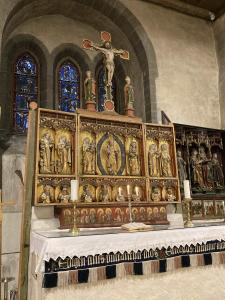A gilded medieval altarpiece with a crucifix on top, at the front of Trondenes Kirke