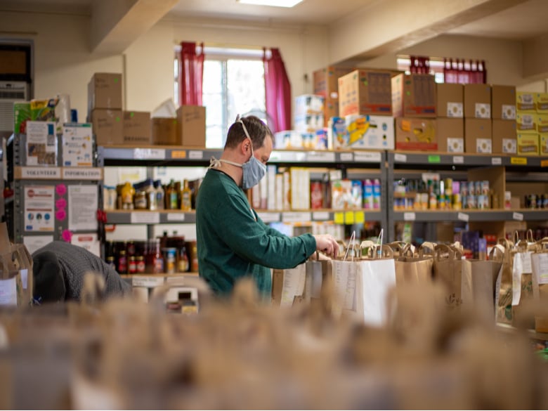 A volunteer assembling bags filled with food in a food pantry.