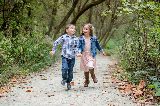 two kids holding hands running in the woods