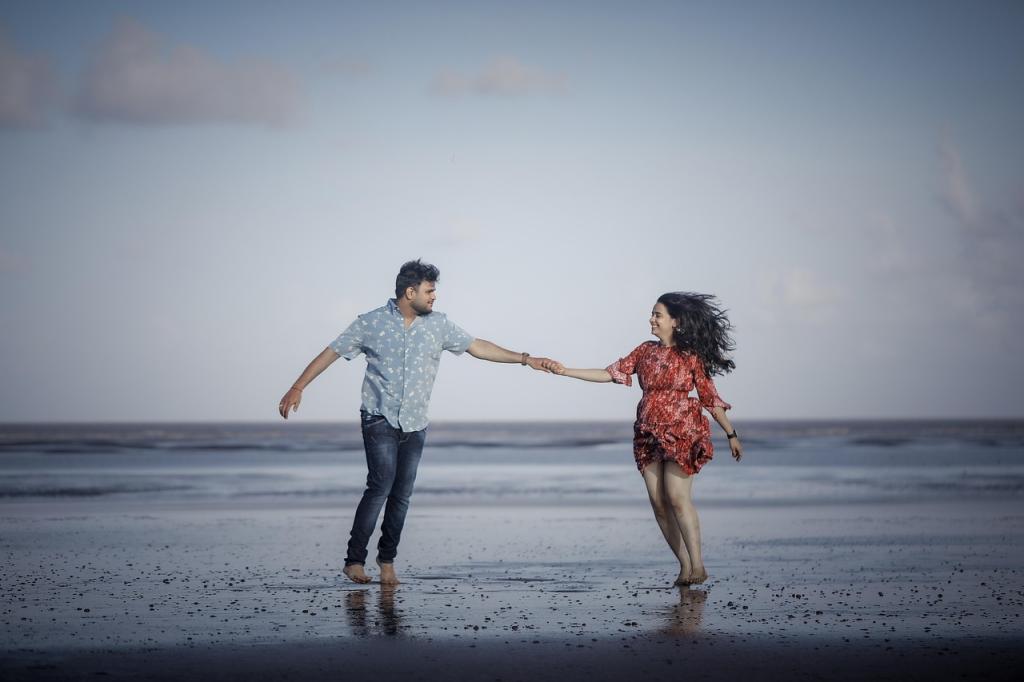 man and woman at the ocean, standing in the water holding hands and looking at each other