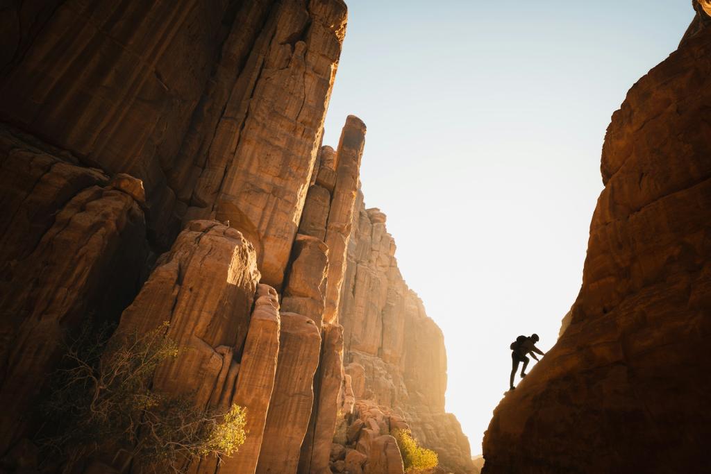 man climbing up side of mountain