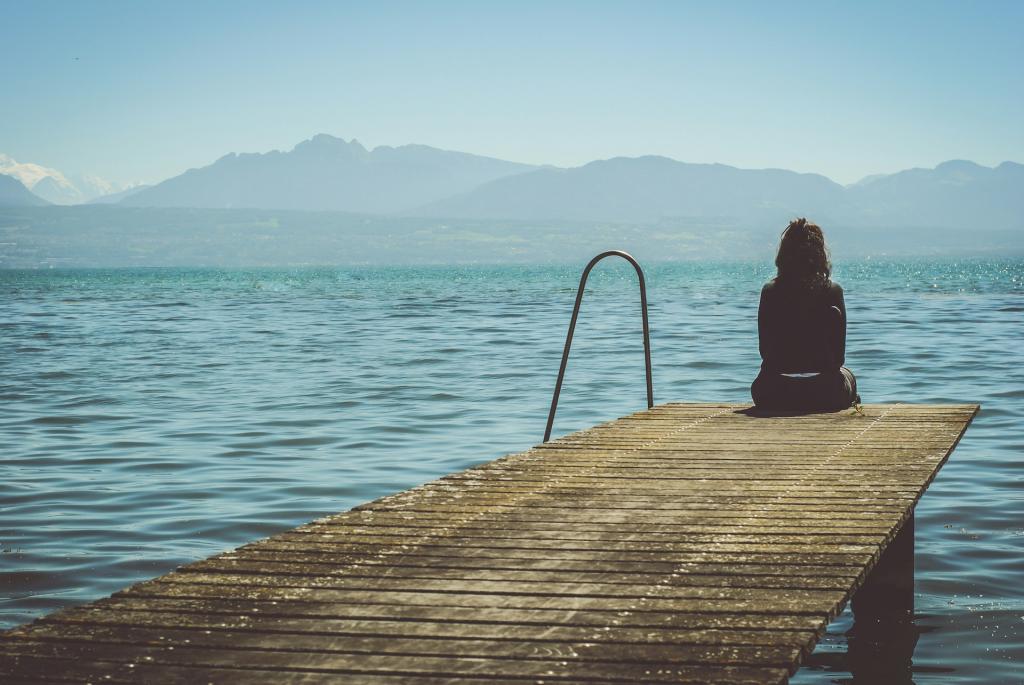 lady sitting on edge of dock over water