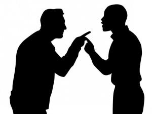 Silhouetts of older white man arguing with younger black man