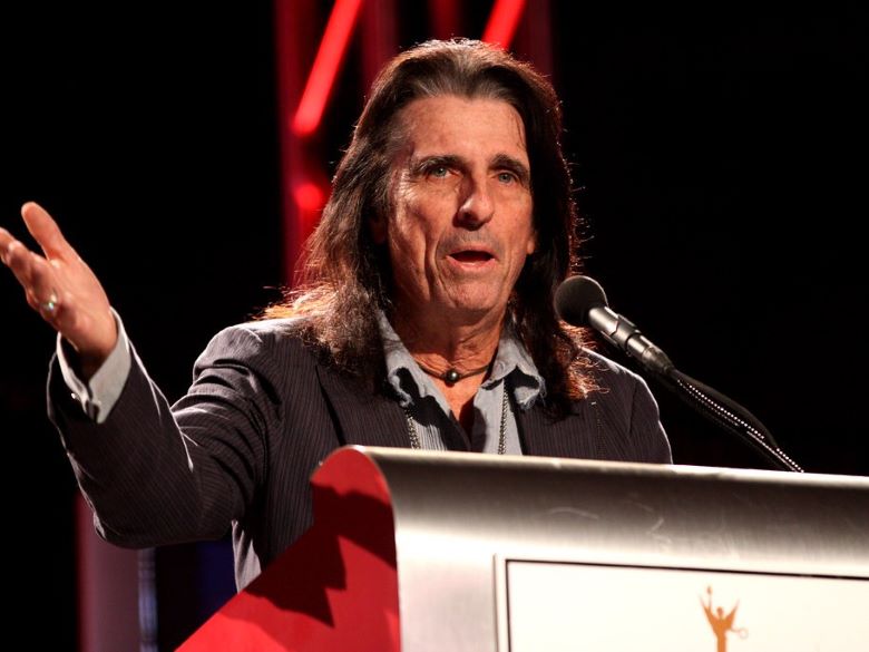 Alice Cooper, without makeup, speaking at a podium