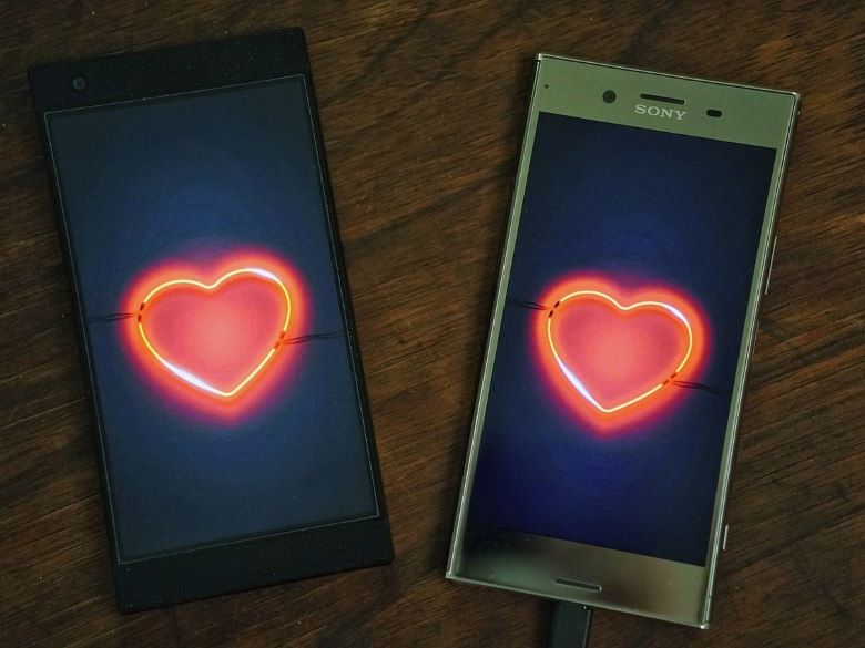 Two smartphones, each with an image of a red neon heart
