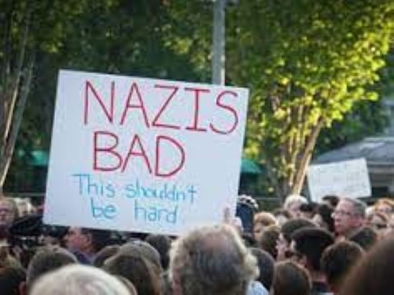 Crowd at vigil. Sign in foreground reads: "Nazis bad. This shouldn't be hard."