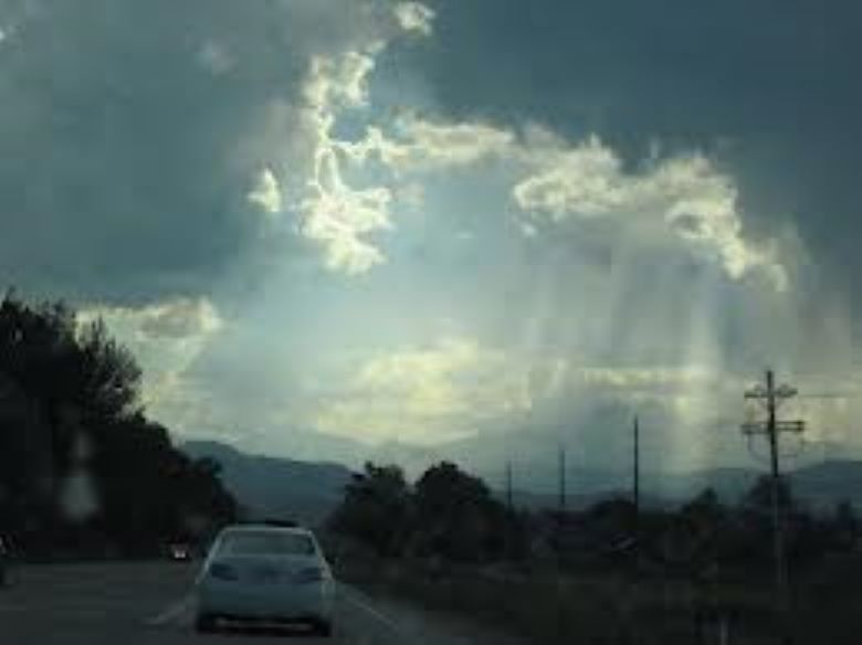 View of sun behind clouds from a road