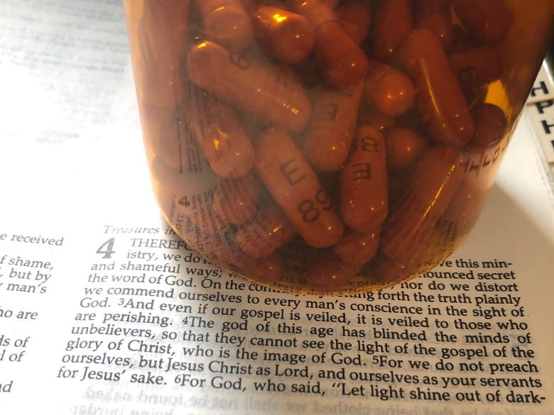 a bottle of antidepressants on a Bible open to 2 Corinthians 4.