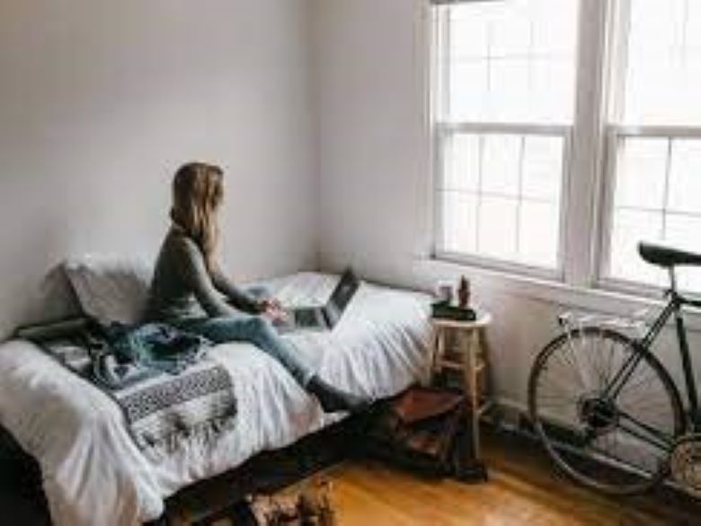 Woman in gray shirt sitting on bed