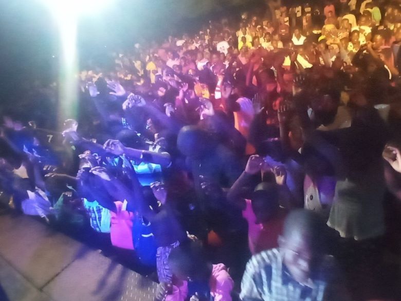 Enthusiastic crowd of worshippers at a nighttime service in Uganda.