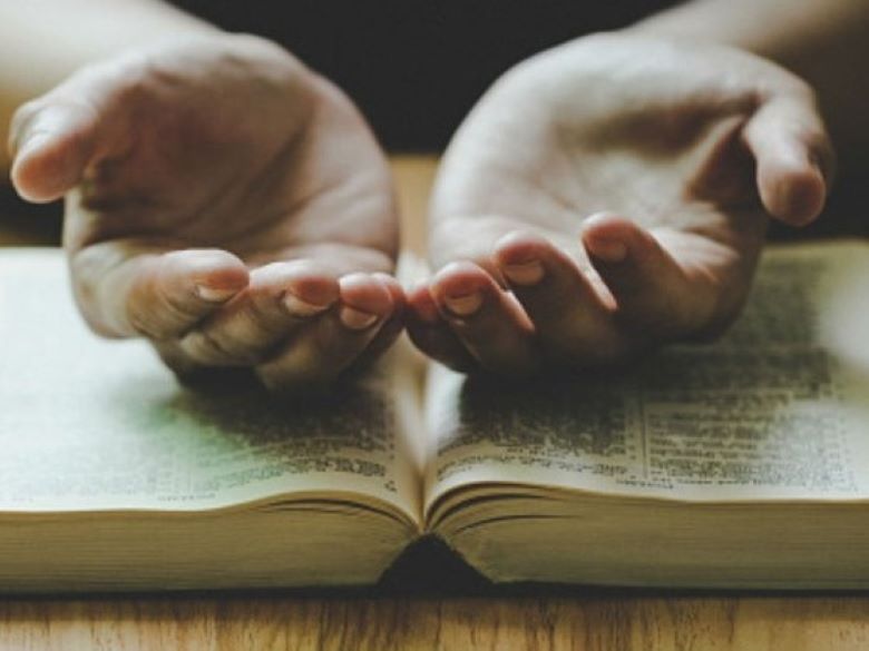 Open hands atop an open Bible