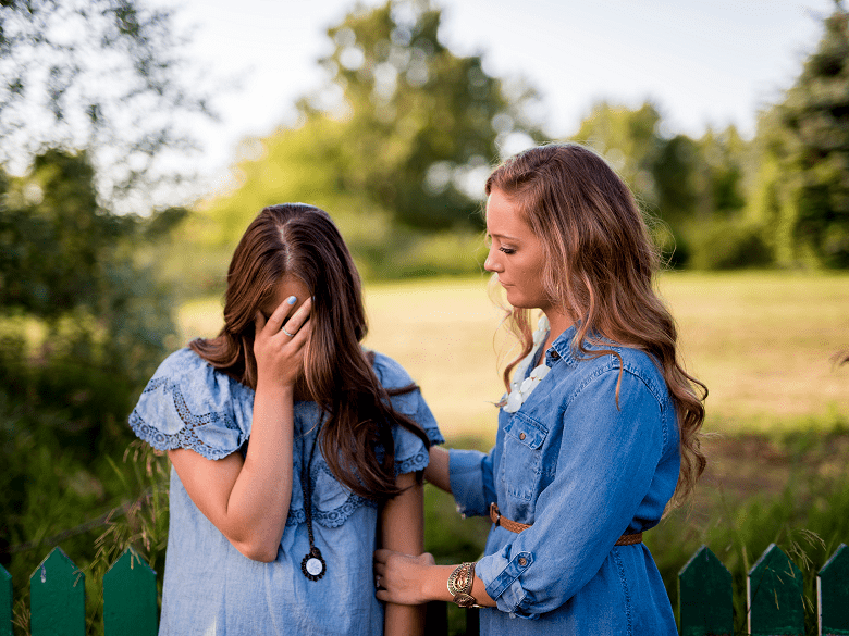 one female friend comforting another female friend