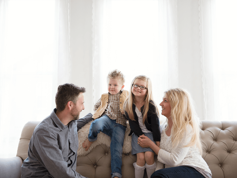 Parents and two young children sitting on couch