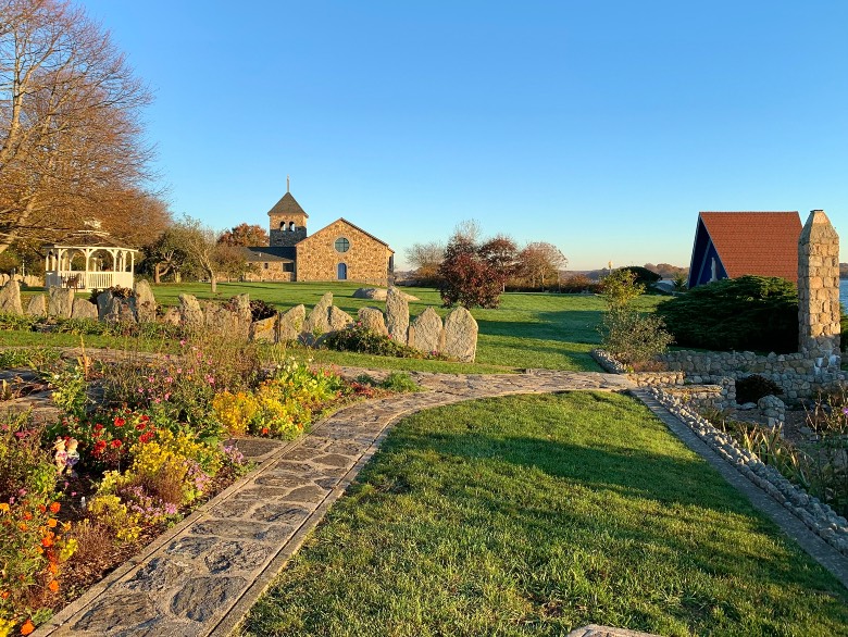 Gardens with stone walkway, wall, and church at Enders Island, CT