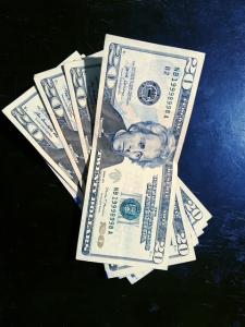 Four US twenty dollar bills fanned out on a table.