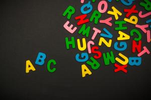 Alphabet magnets scattered on a black background with ABC separated from the rest.