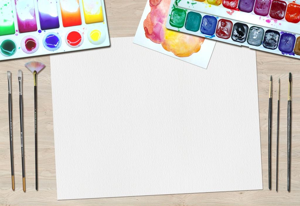 Water color paper with paint brushes on both sides and water color paint palettes at the top.