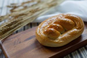 Circular challah loaf on cutting board.