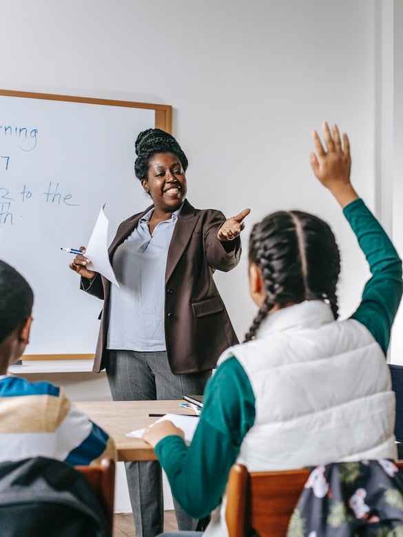 a student raises her hand and is called on by the teacher