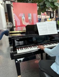 public piano at airport, hand of player is visible on keys