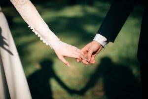 bride and groom holding hands; picture shows sleeved arms and fingers making contact
