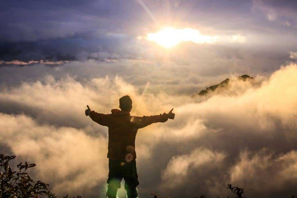 Single person with outstretched arms surrounded by clouds