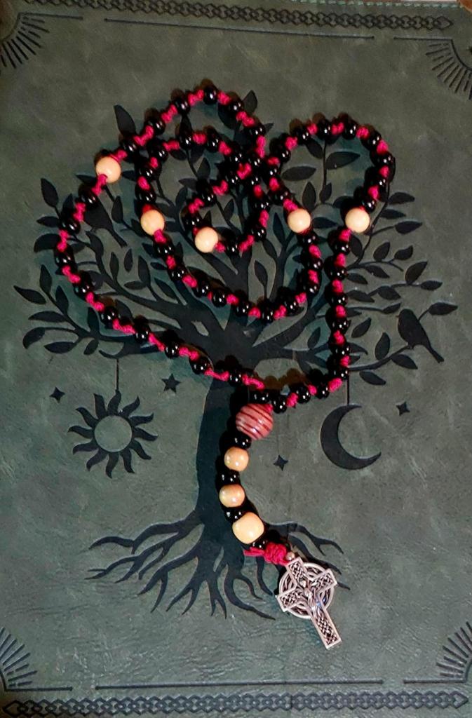 prayer beads on a grimoire with a tree on it