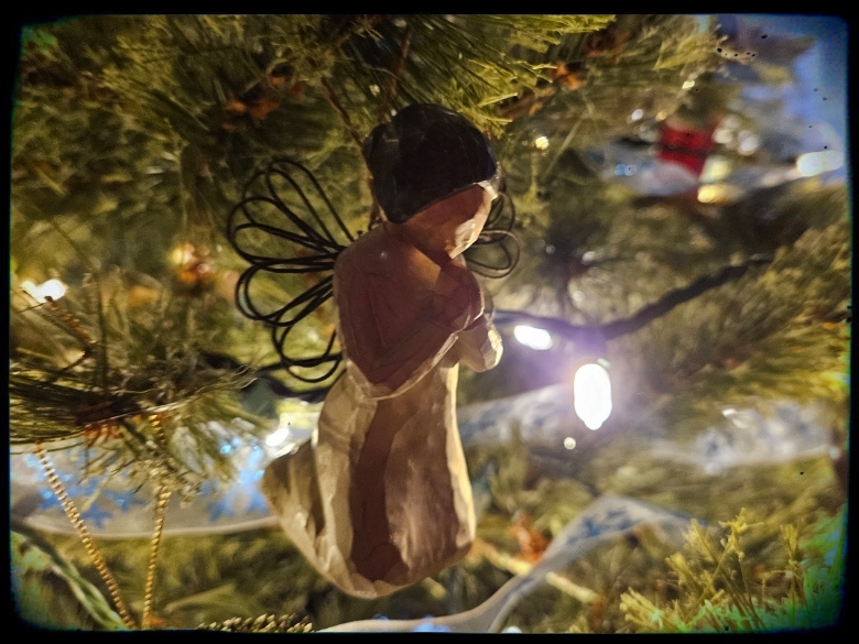 Jesus Lights the Darkness. Angel ornament on Christmas tree with twinkling light.
