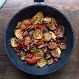 A cast iron skillet of cooked vegetables prepared as a ratatouille