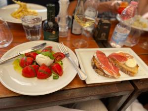Picture of a tabletop with a plate of tomatoes and mozzarella cheese and another plat of bread and prosciutto