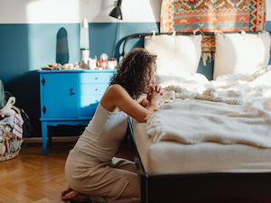 Woman kneeling at bedside praying