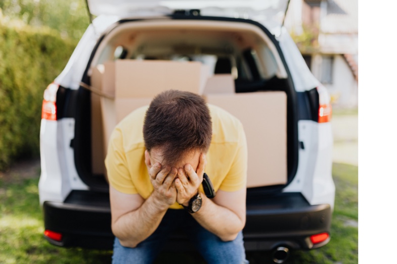 man sitting on back of truck with face in hands