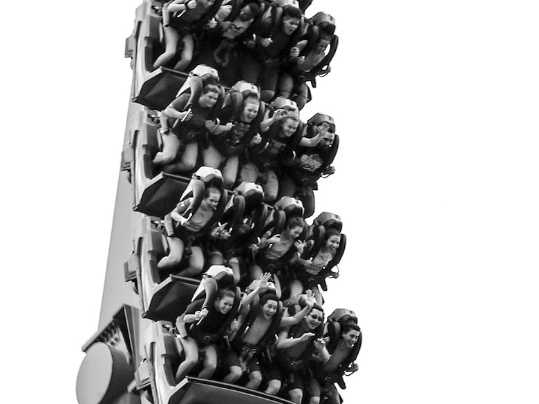 Black and white photo of excited riders on a loop rollercoaster with over-the-shoulder-restraints in place