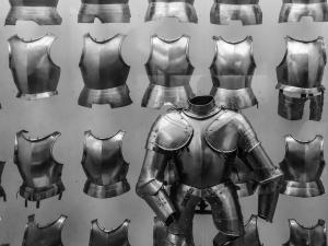 Various types of breastplates from suits of armor, with a more complete suit in the foreground