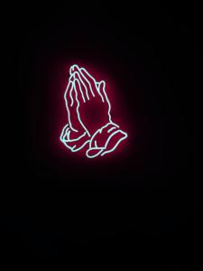 Neon prayer hands on dark background