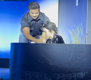 Man baptizing a teenage boy in a blue baptism pool