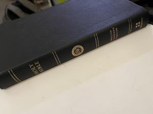 Black leatherbound Holy Bible, ESV, on a white table