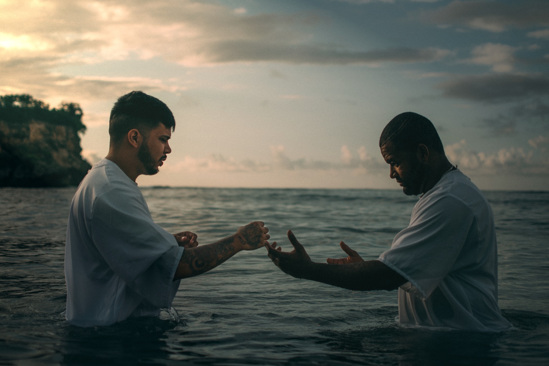 two men standing in a large body of water in preparation for baptism