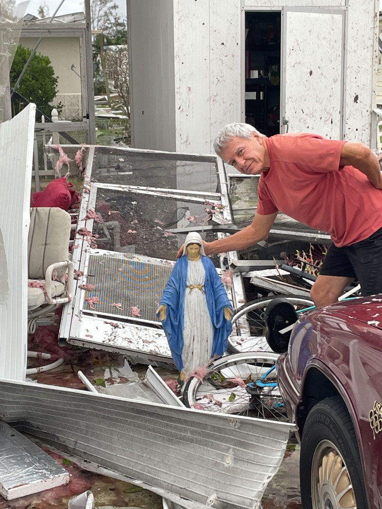 man holds sculpture up after the storm, found in the wreckage