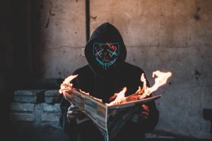 person wearing mask with newspaper on fire