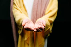 person in robe extending hands out in mercy