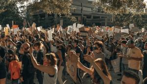 Group of people with arms raised holding signs in protest