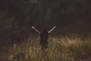 Person in a field with arms extended upward