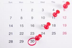 Calendar with many pushpins and a red circle around the 30th