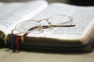 Photo of open Bible with glasses on top.