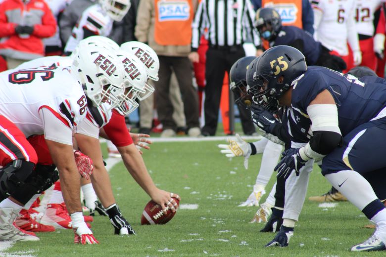 Players from two football teams face each other before the snap.