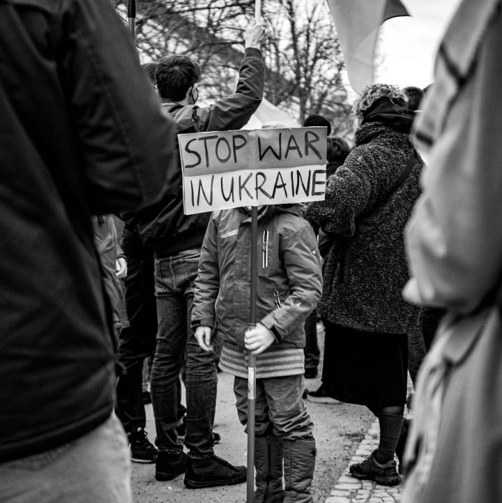 A child holds a sign in the crowd that says "Stop War in Ukraine."