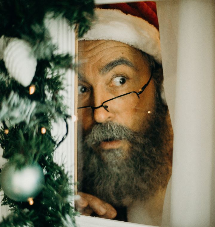 Santa peeks through a window next to the Christmas tree