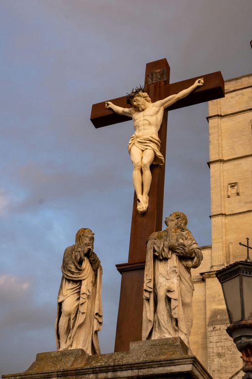 This is a sculpture of Jesus on the Cross with two people standing below